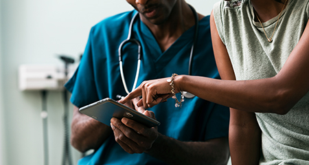 Doctor Shows Patient Information On Digital Tablet - patient pointing